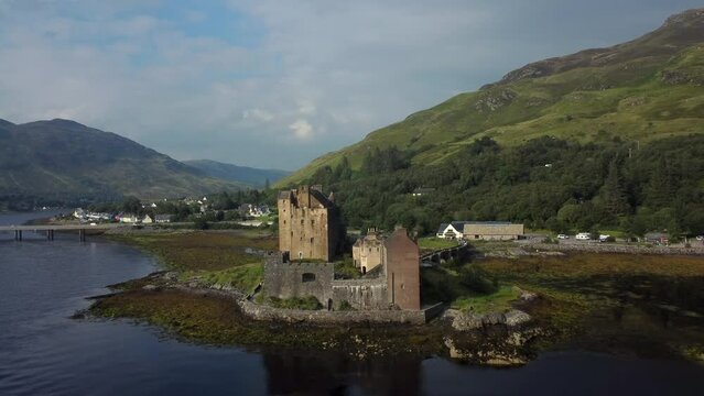 Eilean Donan Castle in the highlands of Scotland, UK _ drone shot sunset with beautiful lake zooming out.