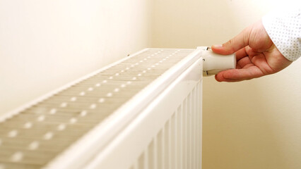 Unrecognizable man's hand check for heat and touch central heating system. White metal heating iron...
