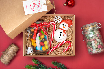 Handmade care package, seasonal gift box with candies, gingerbread, xmas decor on red table Personalized eco friendly basket for family, friends, child, Christmas, Boxing day (26 December) Flat lay  - 668118504