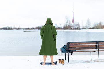 Winter swimming. Man in green warm change robe preparing for the swimming in the cold winter lake