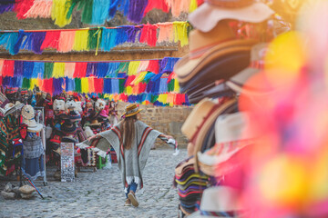 Traveler hipster girl in hat with backpack exploring market of Ollantaytambo Ruins in Sacred Valley...
