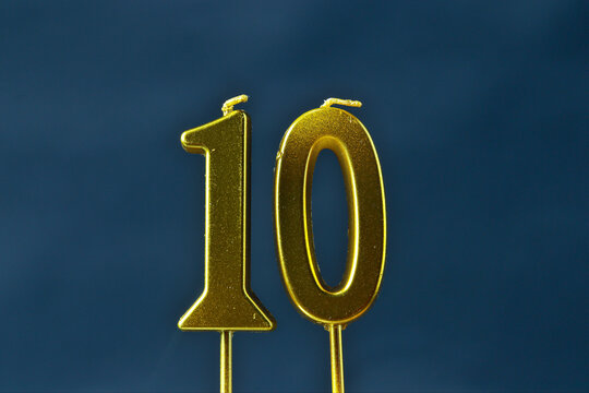 close up on the gold number ten candle on a dark background.
