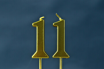 close up on the gold number eleven candle on a dark background.

