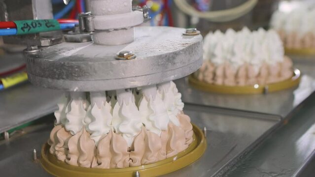 Automated conveyor for creating an ice cream cake. Automated production of ice cream. Ice cream squeezed out of tubes