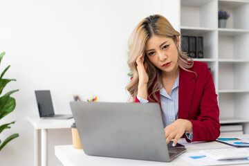 Stressed and irritated Asian businesswoman working on business financial report. and feeling tired and working with laptop and too many documents