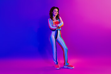 Full body portrait of gorgeous cheerful lady folded hands posing isolated on multicolor effect lights neon background