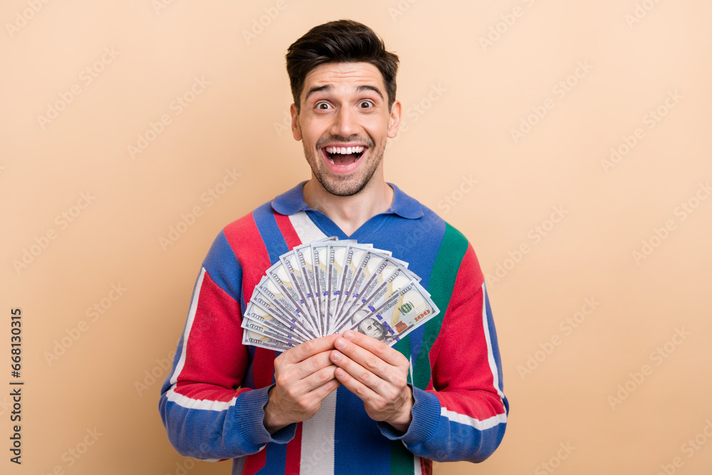 Poster Portrait of impressed positive person open mouth hands hold dollar bills isolated on beige color background