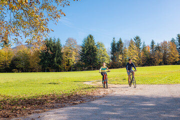 Fototapeta premium Recreational cycling couple enjoying the scenery of a rural area while riding bikes on the country road. Nature, tourism, and active vacation concepts.