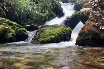 A natural waterfall flowing down rugged rocks covered in moss