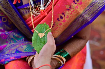 Golden Mangalsutra on green leaf. Married Woman Golden Chain. Indian Wedding Necklace. Maharashtra Culture. Maharashtra Wedding Elements. Holding chain	