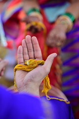Groom Holding Yellow Turmeric Thread for bride. Hand of groom in hindu wedding. Marathi Wedding Ceremony. Maharashtra Culture. Hindu wedding rituals and ceremony	