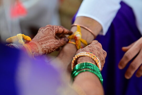 Hands of bride wearing turmeric thread on hand of groom in indian wedding ceremony. Hindu wedding rituals. Hands of bride and groom holding. Wedding worship. Maharashtra culture. Marathi wedding