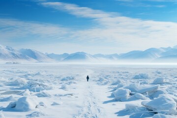 solo traveler walking over frozen lake discovering the winter landscape  rear view of man standing looking at snow covered frozen mountain wilderness - obrazy, fototapety, plakaty