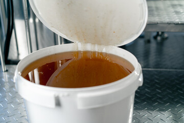 The hand of a technologist opens a barrel of natural liquid honey to be added to production of...