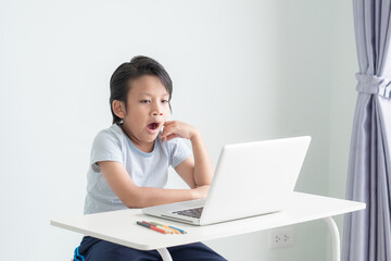A little boy is so tired and yawning while learning online class. An asian kid is sleepy and bored...