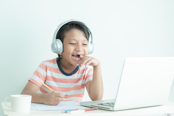 Happy Asian school boy learning online using a laptop computer and headphones with happiness