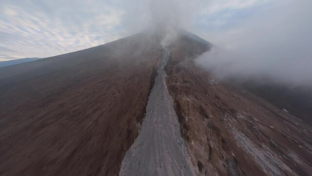 Drone raising active volcanic crater summit natural gas stream danger heat extreme. Aerial morning view approaching eruption volcano peak smoke falling stones disaster eructation explosion landscape