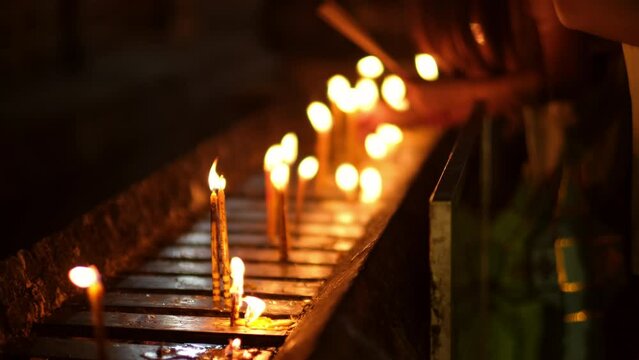 Asian people lighting candles to paying homage Buddha in temple to make a wish on the traditional Songkran festival in Thailand.