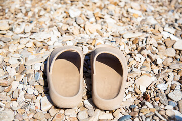 woman's flip-flop beige color on the pebbles on the beach 