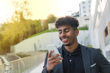 Smiling businessman using phone in the morning in the street