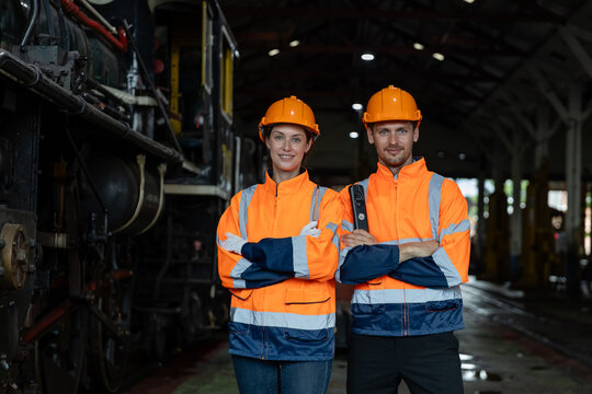 Portrait team engineer train arms crossed standing at train diesel engine in maintenance center. Team railway engineer Inspect repair project train diesel.