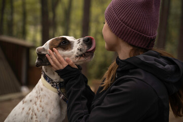 Outside a Glamping , The girl wearing a woolen cap plays with her dog in the middle of nature...