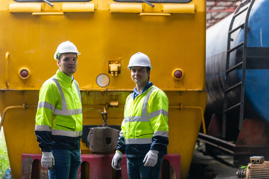 Team railway engineer Inspect repair project train diesel engine in maintenance center. Technician discuss planning checking vehicle and railroad systems.