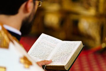 A priest with a prayer book in the church for the service.