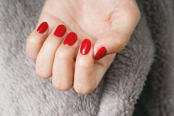 Beautiful female hand painting acrylic gel red nails. Fashion style.