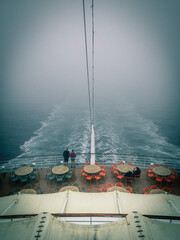 Heck eines Kreuzfahrtschiffes im trüben Nebel zieht eine Spur durch das Meer - 668183116
