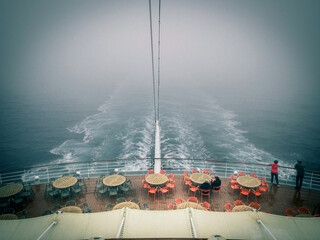 Heck eines Kreuzfahrtschiffes im trüben Nebel zieht eine Spur durch das Meer - 668183197