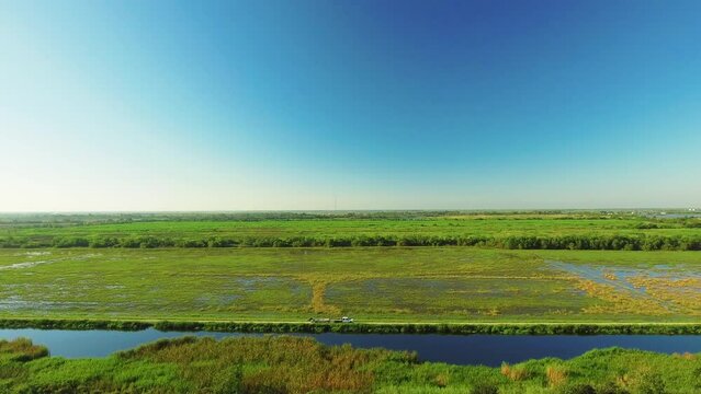 Aerial Panning Backward Shot Of Green Landscape With River Against Blue Sky - Bayou, Louisiana