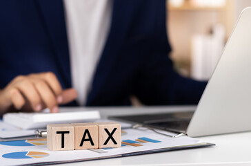 Corporate and individual tax payment concept, Wood blocks text TAX and Businessman filing taxes on laptop financial planning and Corporate tax,Income tax return and VAT calculation government revenue. - obrazy, fototapety, plakaty