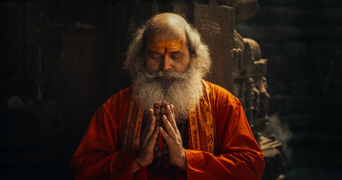 Slow-Motion Close-Up of Old Indian Monk Chanting in an Ancient Temple. The Senior Guru Sings Religious Songs, Humbly Chating Sacred Mantras, Showing Devotion and Love in Moment of Emotional Worship