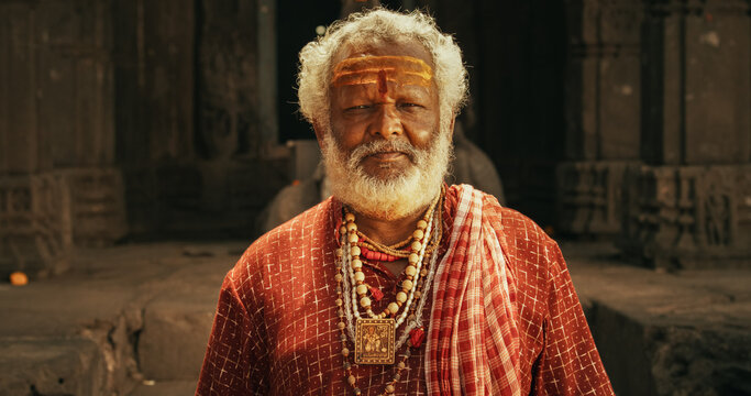 Portrait of a Senior Hindu Monk Looking at the Camera and Smiling in an Ancient Temple. Friendly Indian Senior Man Posing as he is seeking Guidance and Wisdom from his Religion