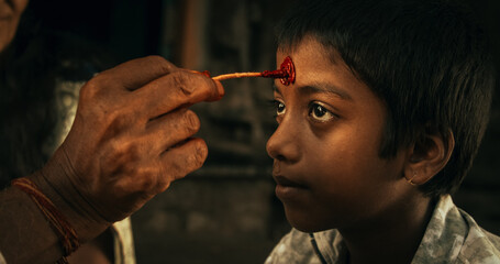 Authentic Footage of Hindu Priest Putting a Tilaka on Male Kid in a Temple. Senior Guru Giving Blessings with a Mark on the Forehead to a Child, Faithful Worshipers in Religious Ceremony - obrazy, fototapety, plakaty
