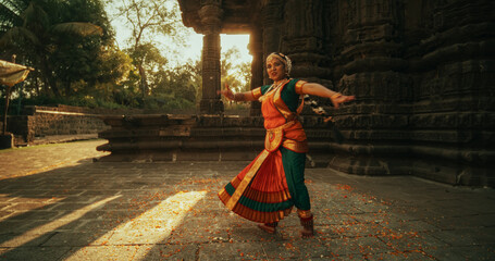 Shot of Indian Woman in Traditional Clothes Dancing Bharatanatyam in Colourful Sari While Looking...
