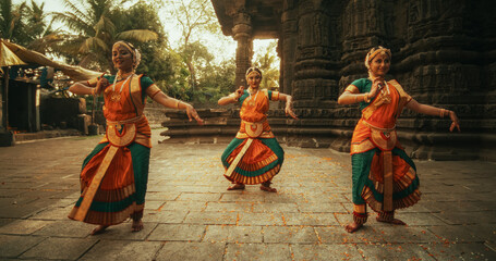 Portrait of Three Expressive Young Indian Dancers Performing Folk Dance Choreography in an Ancient Temple. Women in Traditional Clothes Dancing Bharatanatyam in Colourful Sari