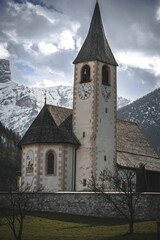 Vertical shot of a historic chapel and clock tower in the Dolomites