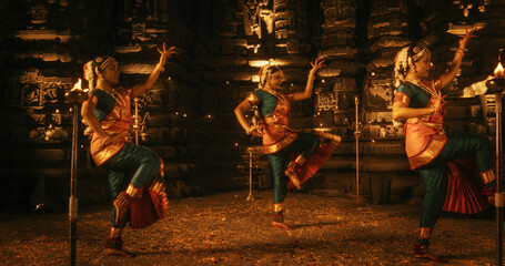 Portrait of Three Expressive Young Indian Dancers Performing Folk Dance Choreography Inside an...