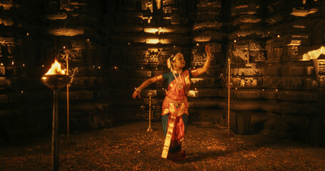 Portrait of Young Energetic Indian Woman Performing Traditional Folk Dance Inside a Candle-Lit Temple. Enchanting Cultural Display in Historical and Spiritual Site