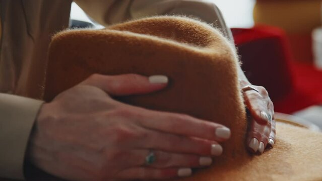 Close-up shot of female hands taking off cheesecloth from recently ironed hat