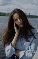 Stylish young woman. Close-up portrait of a beautiful girl with brown hair looking at the camera outdoors in the city