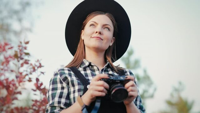 Portrait of young photographer woman with DSLR camera on autumn sky background