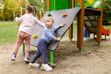 Two kids playing on playground outdoors.