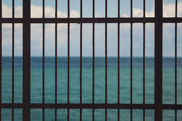 Protective mesh on a blue sea background.  iron fence on a blue sea and sky background. 