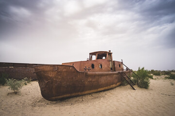 Fototapeta na wymiar Rusty ships and boats in the desert at the bottom of the dried up Aral Sea in Uzbekistan, an ecosystem tragedy