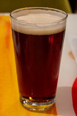Pint glass of cold fresh british ale and lager beer served in old vintage English pub