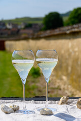 Tasting of grand cru sparkling white wine with bubbles champagne with view on old houses of Oger, small village with grand cru vineyards, France.