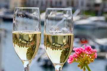 Drinking of French brut champagne sparkling wine in glasses, club party in yacht harbour of Port Grimaud near Saint-Tropez, French Riviera vacation, France